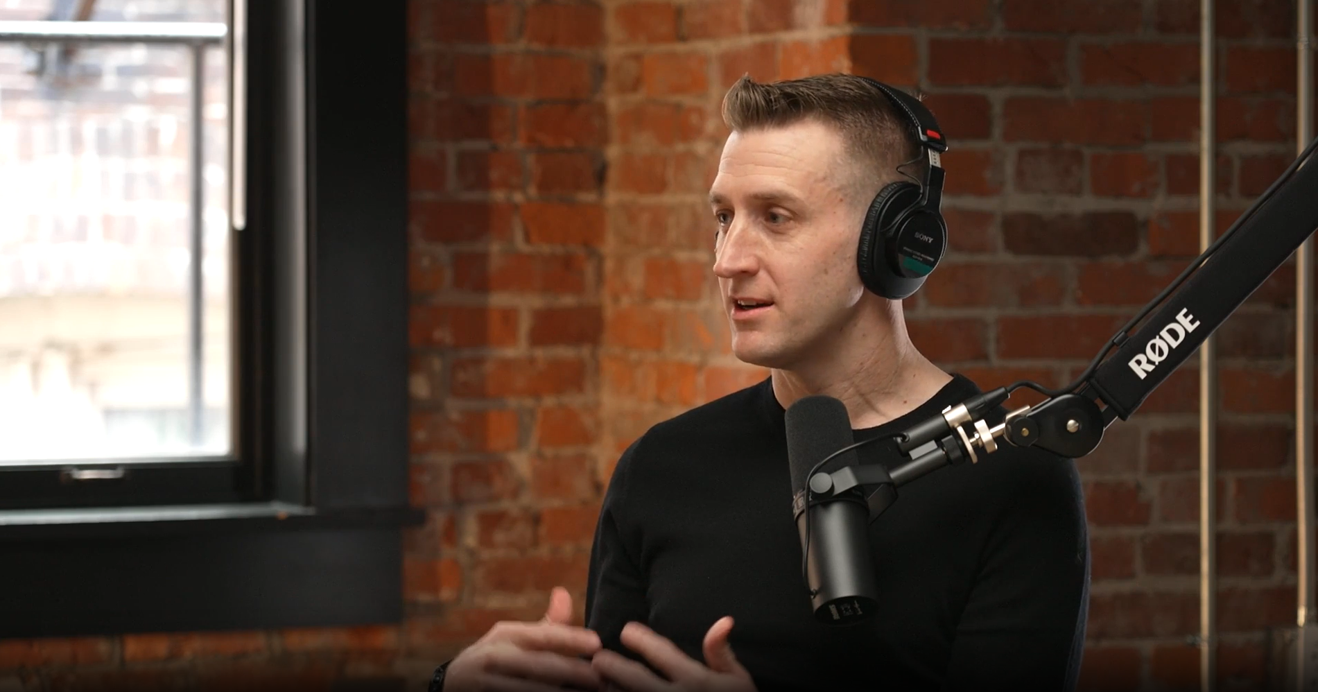 Brian Houck wearing headphones and speaking into a studio microphone.